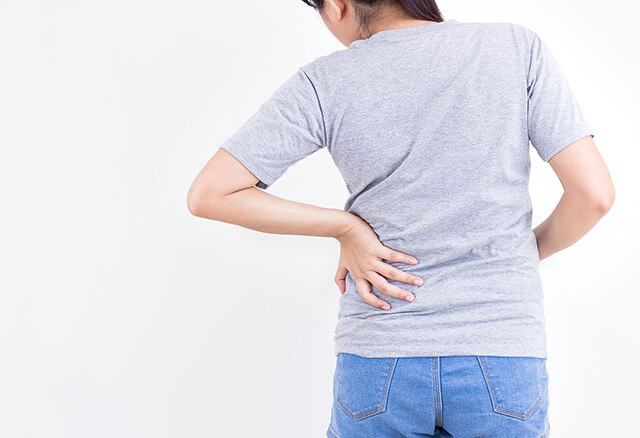 左背部を手でおさえる中年女性